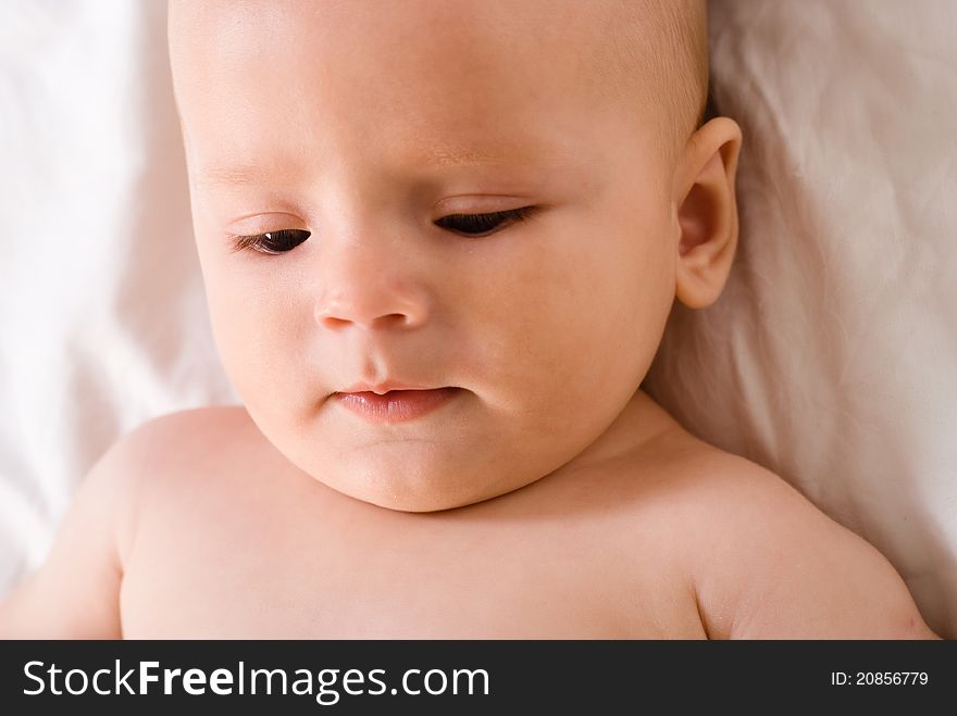 Portrait of a cute baby lying on bed on a white