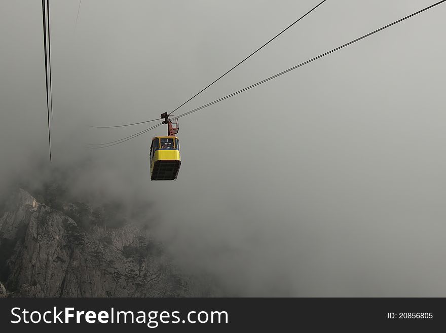 The cable car in Crimea Ai-Petri on a background of mountains covered with clouds. The cable car in Crimea Ai-Petri on a background of mountains covered with clouds