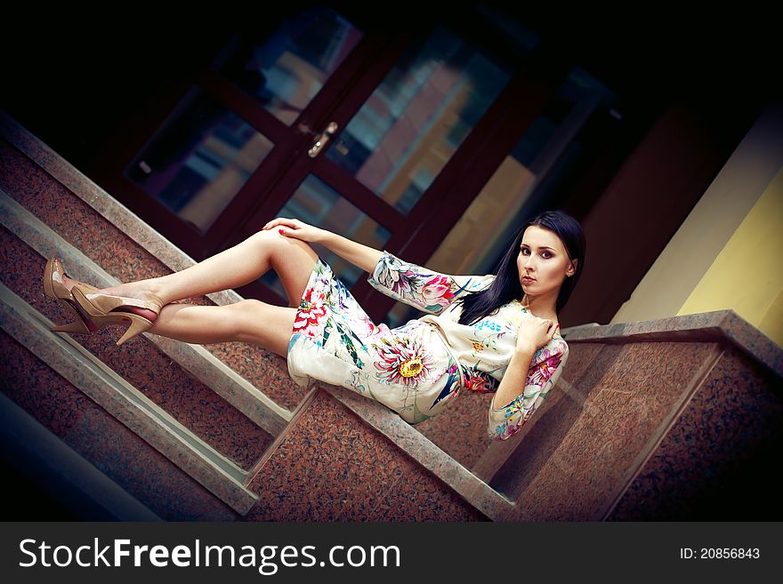 Stunning brunette sitting and posing in fashion dress