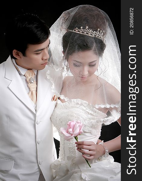 Portrait of young groom looking to his bride holding pink flower