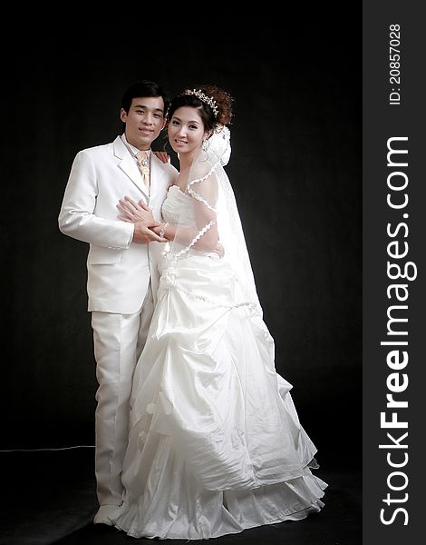 Portrait of young bride and groom standing in black background