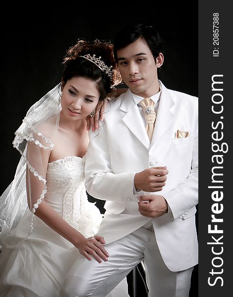 Portrait of young bride and groom standing in black background