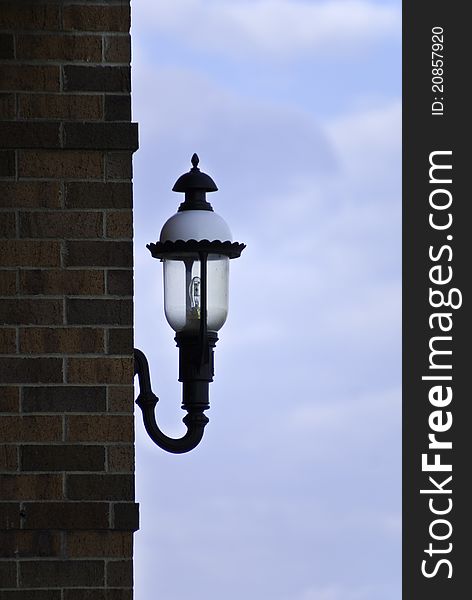 An ornate lamp on the outside of a building with the bright blue sky behind. An ornate lamp on the outside of a building with the bright blue sky behind.