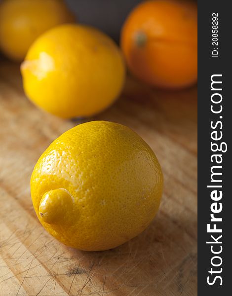 Lemon and orange on wooden chopping board, ready for preparation to eat.
