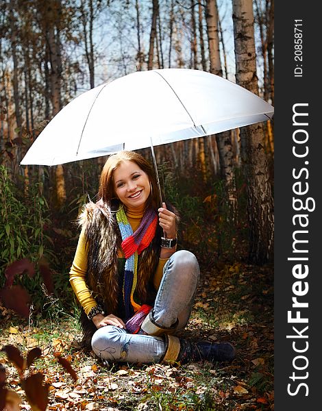 Young attractive smiling girl under umbrella in autumn forest. Young attractive smiling girl under umbrella in autumn forest