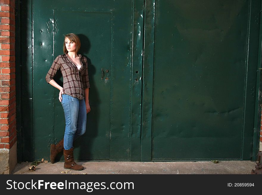 A young woman standing by s apir of green doors. A young woman standing by s apir of green doors