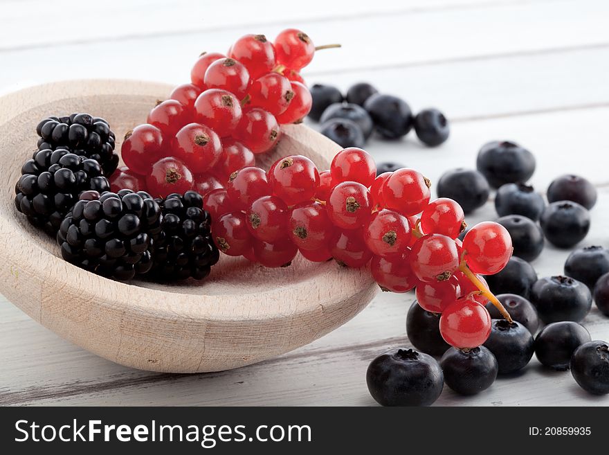 Bramble berries, currants and blueberries on a white rustic table. Bramble berries, currants and blueberries on a white rustic table