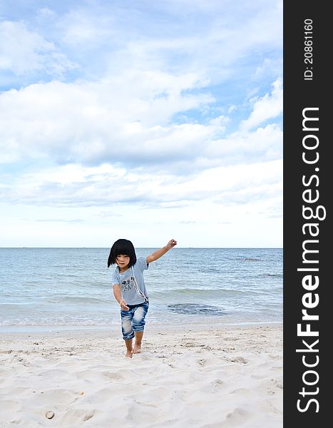 Little asian girl running on the beach with blue sky