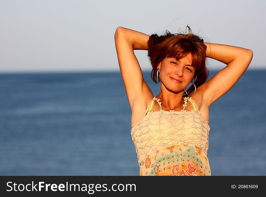 Attractive woman holding her hair on a sea (ocean) background outdoor