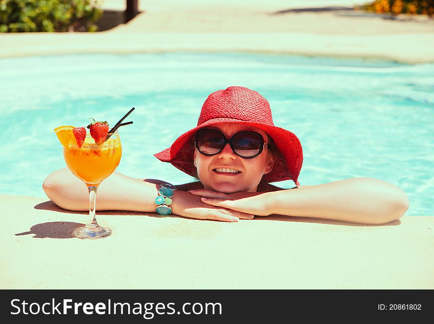 Beautiful woman relaxing in swimming pool with cocktail and smiling. Beautiful woman relaxing in swimming pool with cocktail and smiling