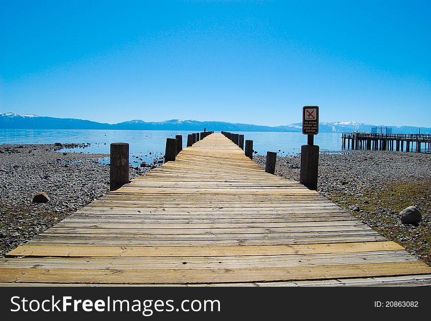 A dock at the north shore in Lake Tahoe, Nevada with the snow capped mountains in the background. Visible is a no diving sign. A dock at the north shore in Lake Tahoe, Nevada with the snow capped mountains in the background. Visible is a no diving sign.