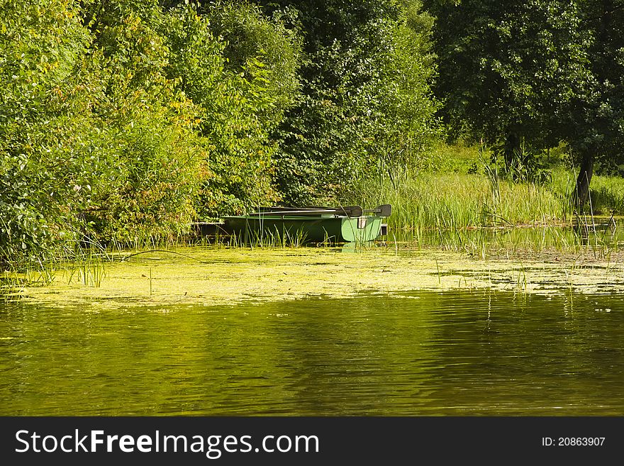 Green boat at lake bank in summer sunny day