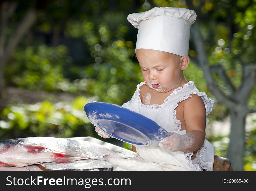 Cute little baby in cook hat holding a blue plate. Cute little baby in cook hat holding a blue plate.