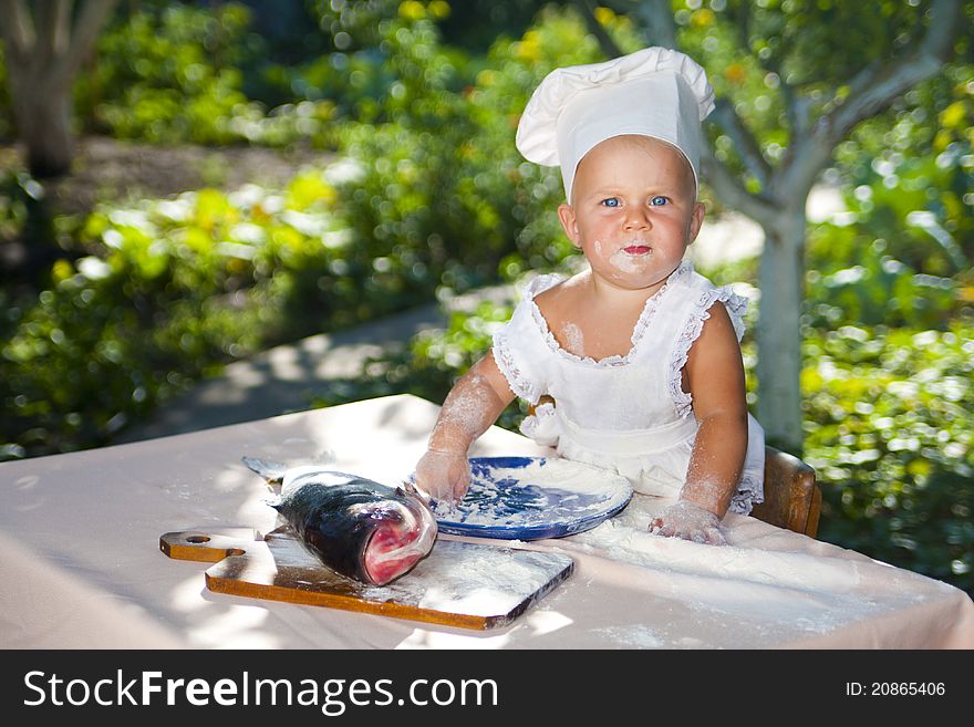 Cute little baby in chef hat ready to cook fish. Cute little baby in chef hat ready to cook fish.