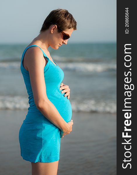 Girl is holding pregnant belly on the beach. Girl is holding pregnant belly on the beach