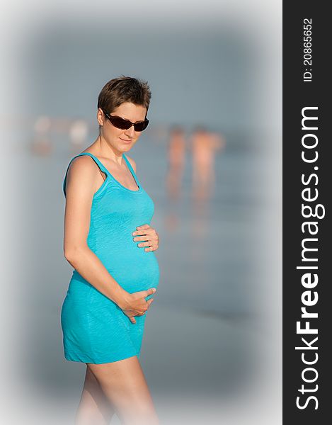 Girl is holding pregnant belly on the beach. Girl is holding pregnant belly on the beach