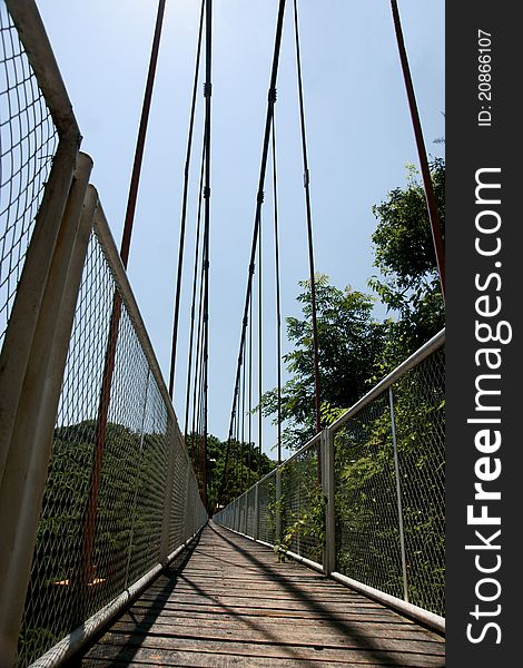Picture of a cable suspension bridge located on the top of a moutain with trees surrounding