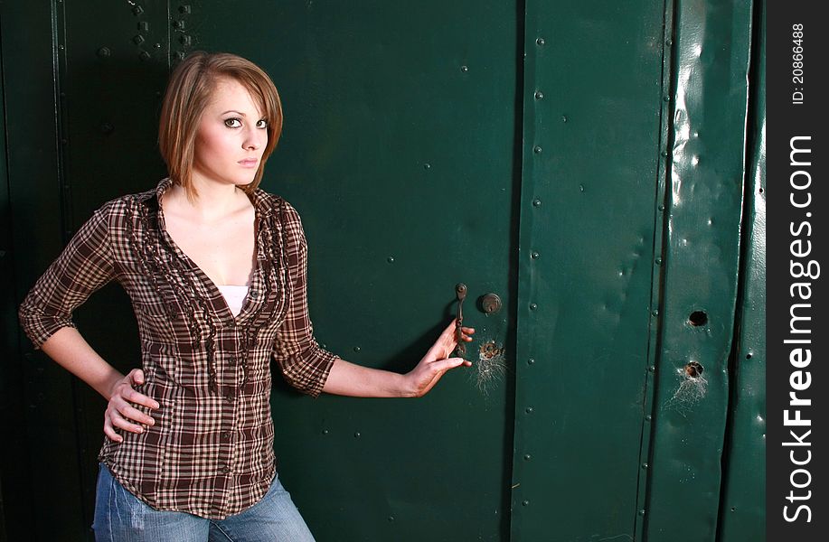 A young woman standing by a green door. A young woman standing by a green door