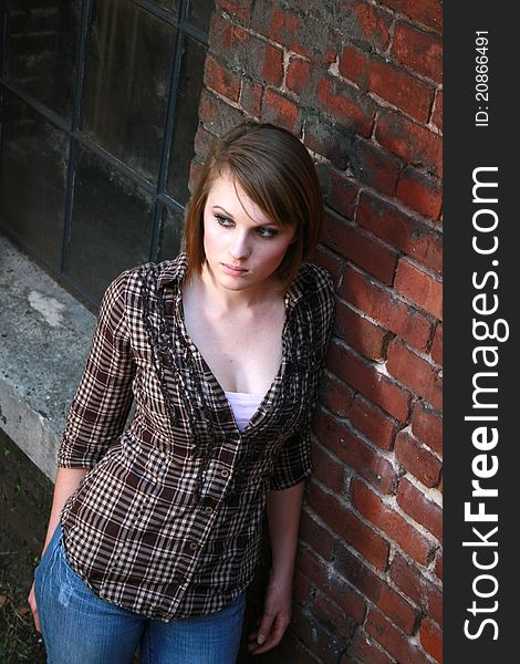 A young woman leaning against a brick wall