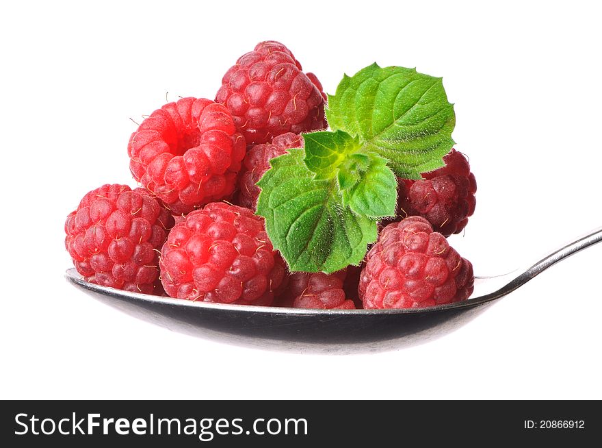 Raspberryes and twig of mint on a spoon, isolated on white