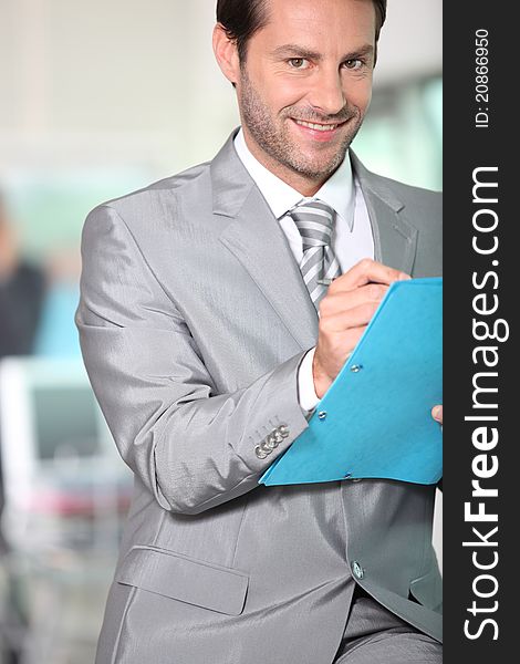 Portrait of businessman writing notes in a blue folder. Portrait of businessman writing notes in a blue folder