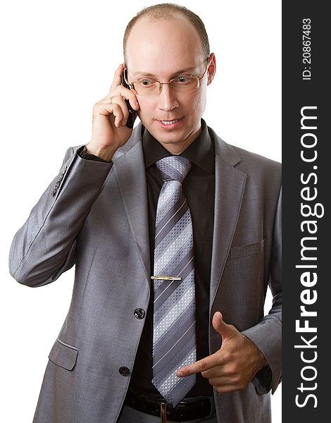 Man in a gray business suit, tie and glasses does business talks on his cell phone on an isolated white background. Man in a gray business suit, tie and glasses does business talks on his cell phone on an isolated white background