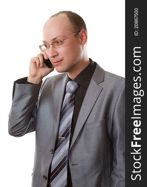 Business man in a gray business suit, tie and glasses does business talks on his cell phone on an isolated white background. Business man in a gray business suit, tie and glasses does business talks on his cell phone on an isolated white background
