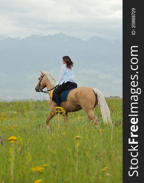 The girl skips on a green field on the horse