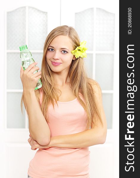 Beautiful girl with bottle of water on a light background