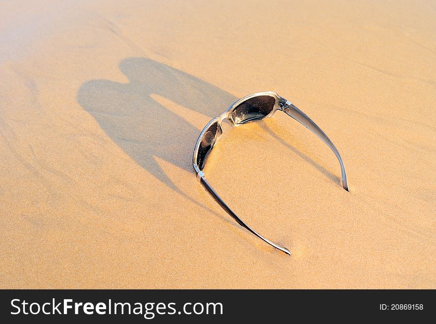 Sunglasses on the sandy beach at the sea