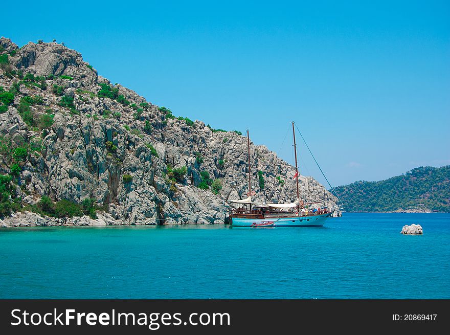 The small white boat is in the beautiful blue sea with mountains and on background blue sky of the Turkey. The small white boat is in the beautiful blue sea with mountains and on background blue sky of the Turkey