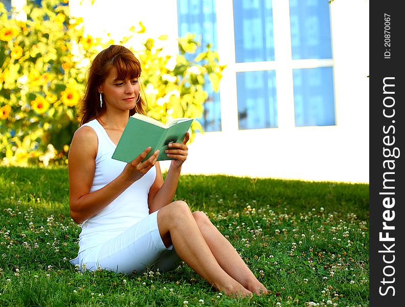 A beautiful woman reading book out in a meadow with sunflowers and windows as a background