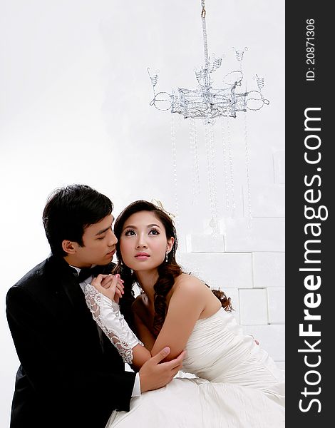 Portrait of young bride and groom in romantic action on white ba