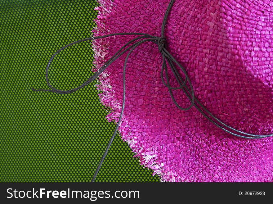 Pink straw hat with string, on green background. Pink straw hat with string, on green background.