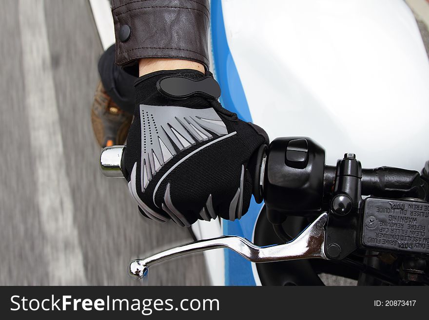 A biker's hand gripping a handlebar as he zooms down the road. A biker's hand gripping a handlebar as he zooms down the road