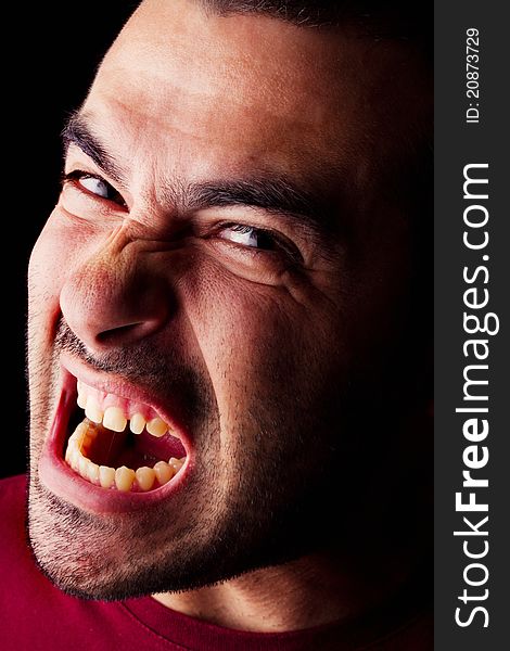Close detail view of a angry young male man isolated on a black background. Close detail view of a angry young male man isolated on a black background.