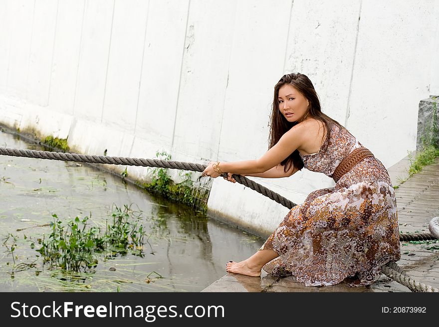 Beautiful girl pulling a rope near river