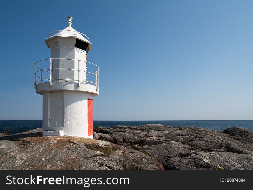 Simple lighthouse on a cliff, overlooking the sea.