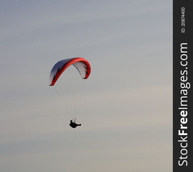 A unrecognizible person paragliding in the sky.