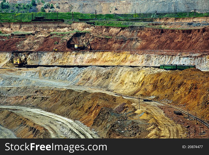 Opencast mine with crawler-mounted power shovels extract and load iron ore into freight trains