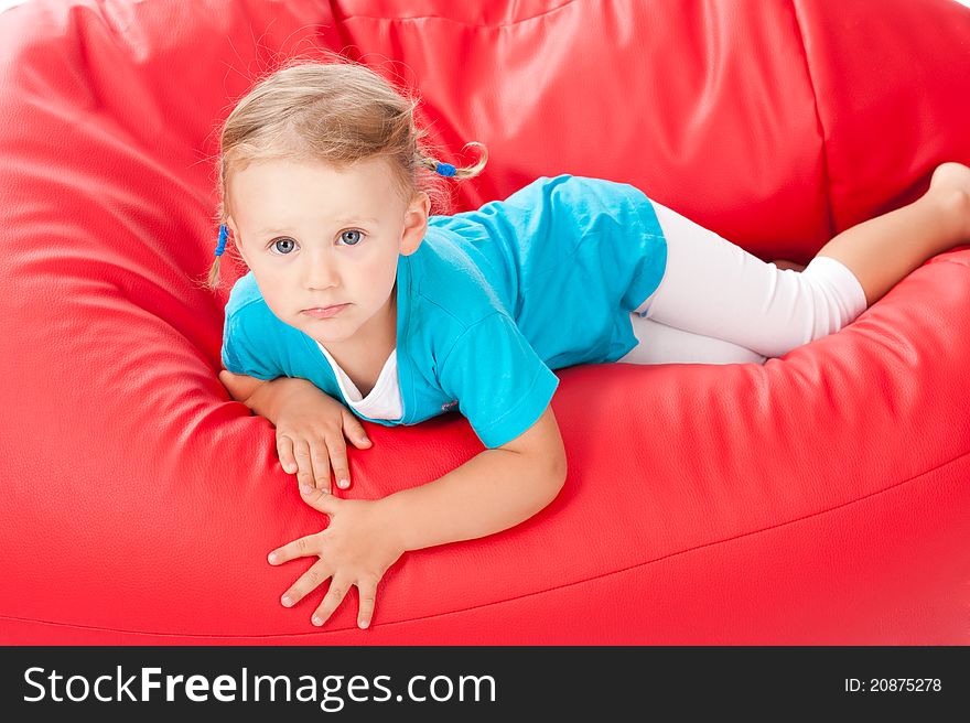 Smiled child on the red pouf chair. Smiled child on the red pouf chair