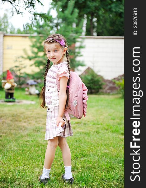 Young school girl with pink backpack poses outdoors. Young school girl with pink backpack poses outdoors