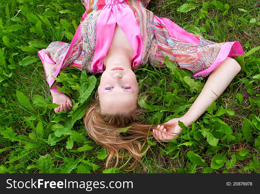 Portrait of a beautiful young woman on the grass in summer