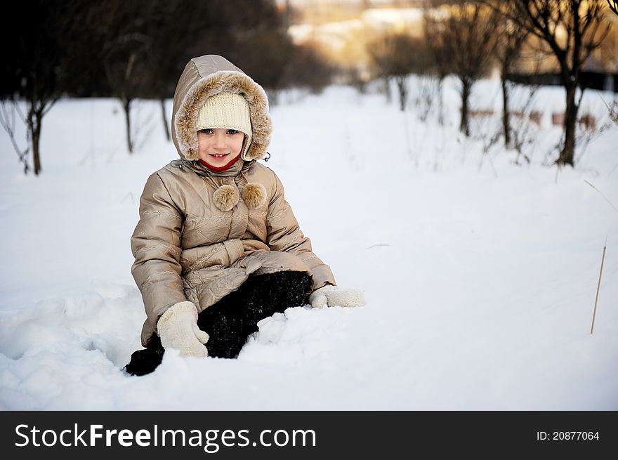 Child girl in winter coat with hood plays in snow