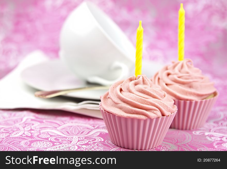Pink cupcake with cream and candle on a pink background