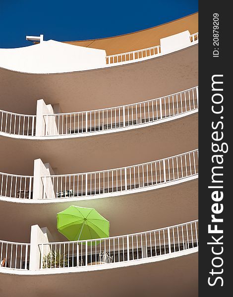 A green umbrella on a balcony of a hotel. A green umbrella on a balcony of a hotel