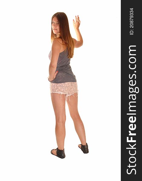 A young girl in a t-shirt and pink shorts, standing on a wall from the back and looking over her shoulder, for white background. A young girl in a t-shirt and pink shorts, standing on a wall from the back and looking over her shoulder, for white background.
