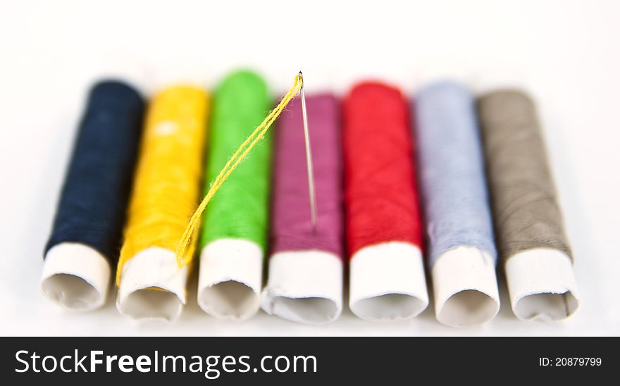 A close up needle with a colorful spools of thread background. A close up needle with a colorful spools of thread background.