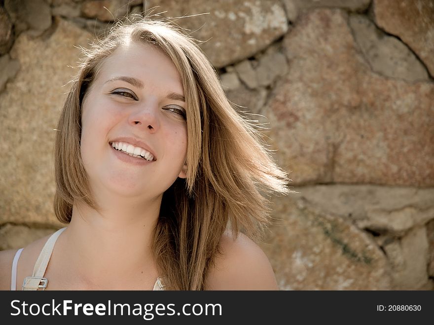 Teen girl happy smiling with background of wall made from natural stone. Teen girl happy smiling with background of wall made from natural stone