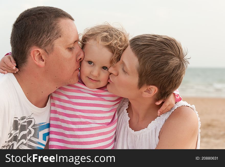 Mother and father are kissinh their baby on beach. Mother and father are kissinh their baby on beach
